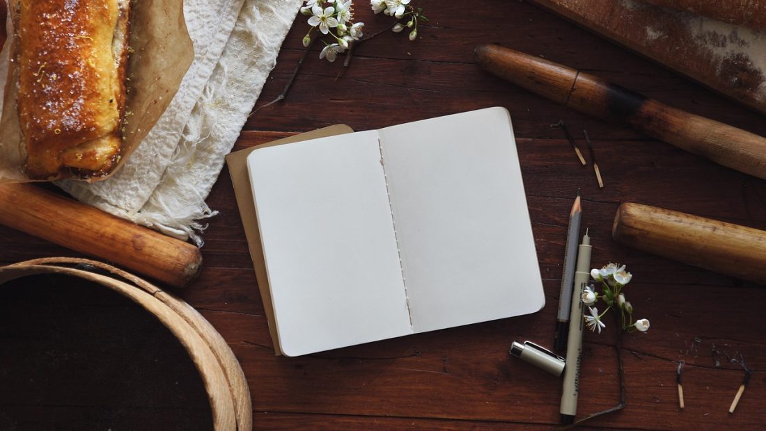 窗边小桌上摊开的 journal 内页，密密麻麻的手写字迹，旁边压着一支旧钢笔和几张票据，午后光线柔和